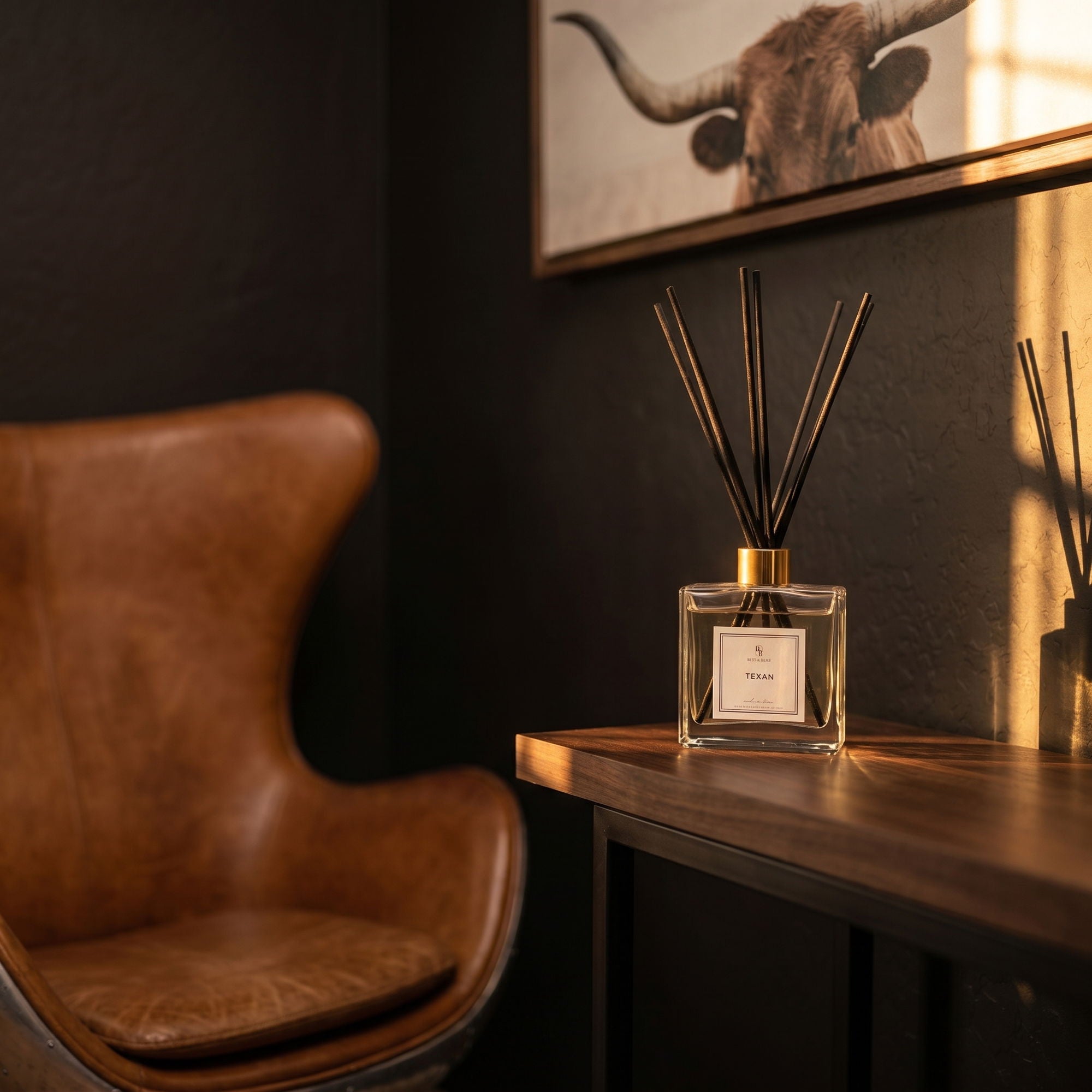 Decorative diffuser on a table next to a brown leather chair with a dark wall and bull head artwork in the background.