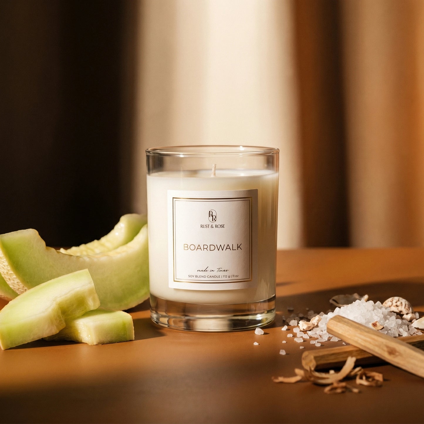 Candle labeled 'Boardwalk' with melon and salt on a wooden surface