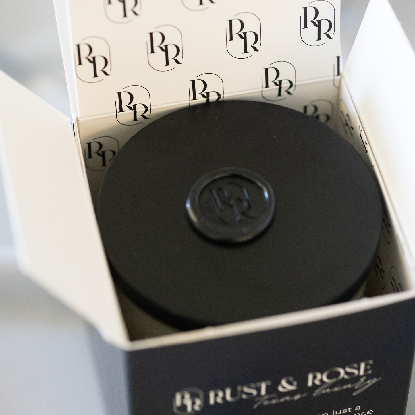 Black container with a logo on top of a box with 'Rust & Rose' branding.