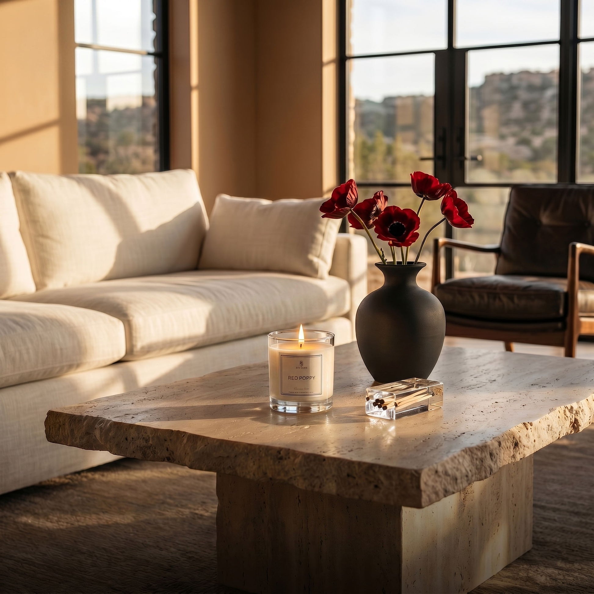 Living room with a stone coffee table, candle, and vase with red flowers.