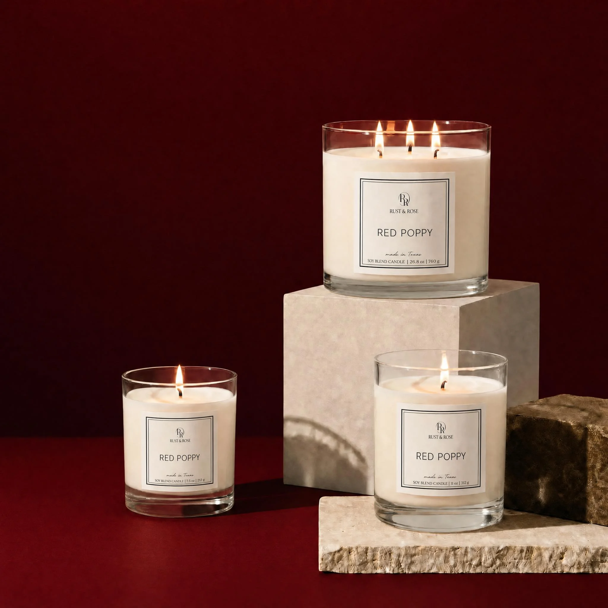 Three 'Red Poppy' candles on a dark red background