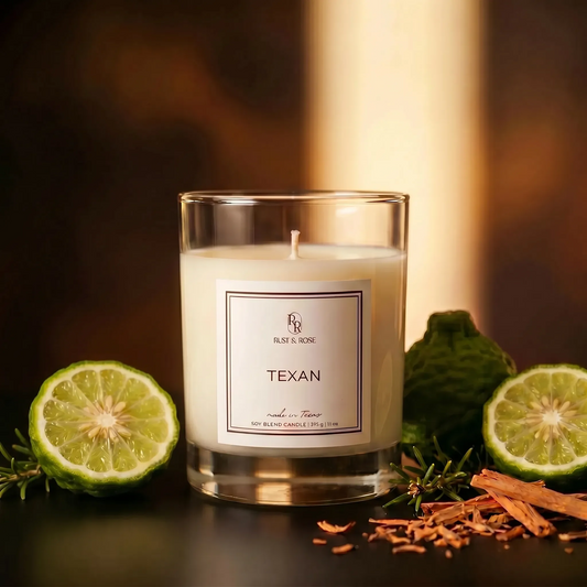 Candle labeled 'Texan' with lime halves and rosemary on a dark surface